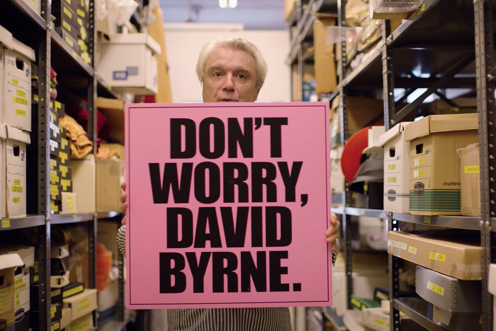 musican David Byrne holds up a sign that say Don't Worry
