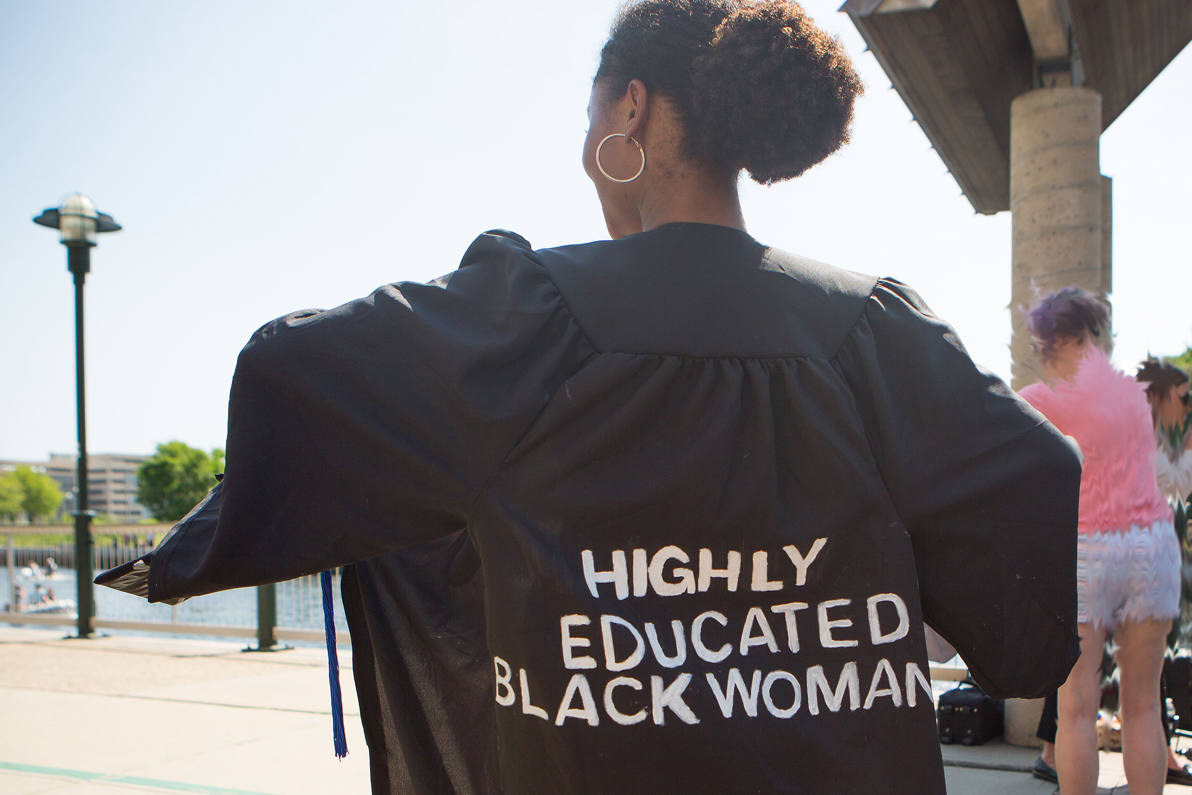 grad with sign on her back reading highly educated black woman