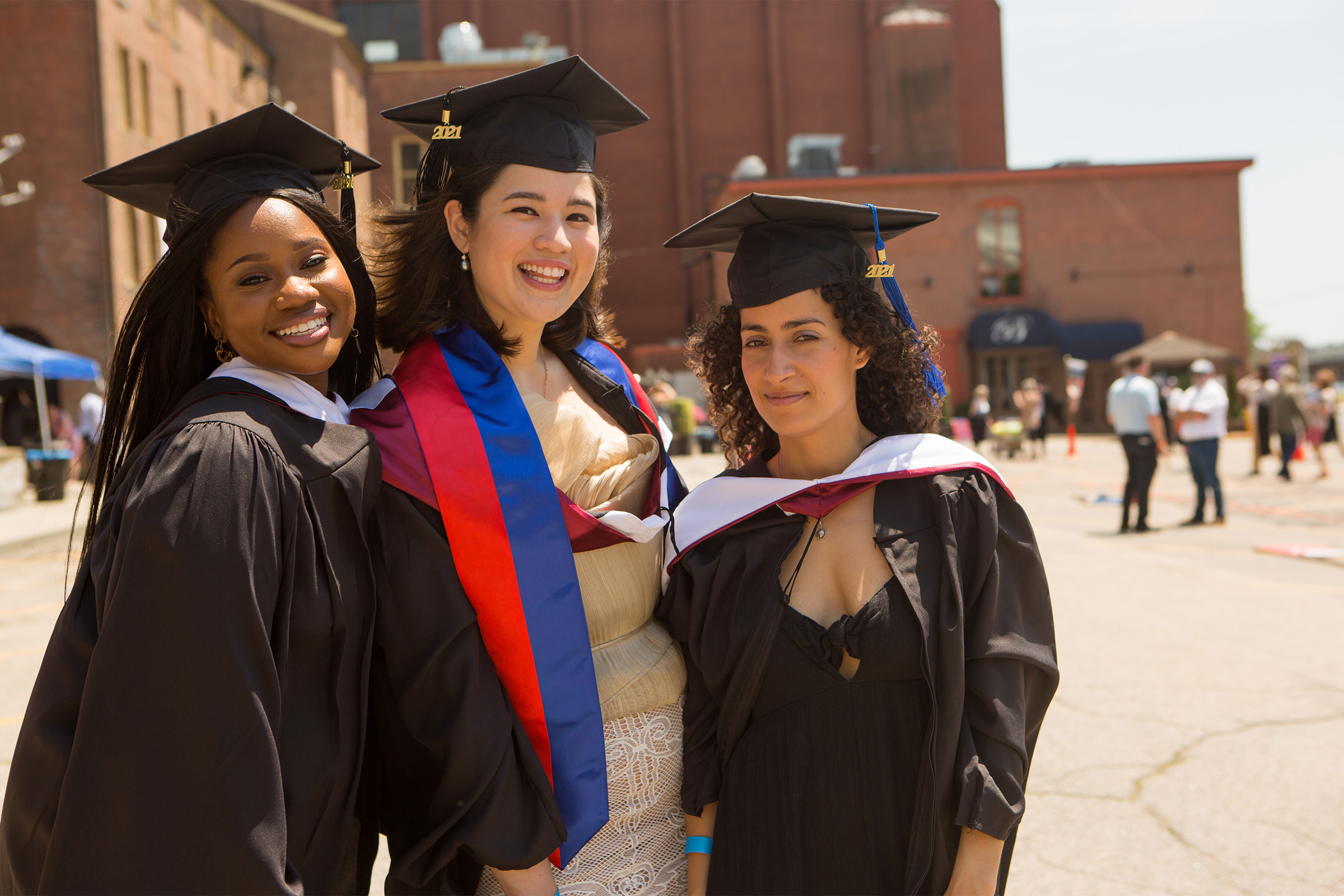three women in caps and gowns pose for the camera