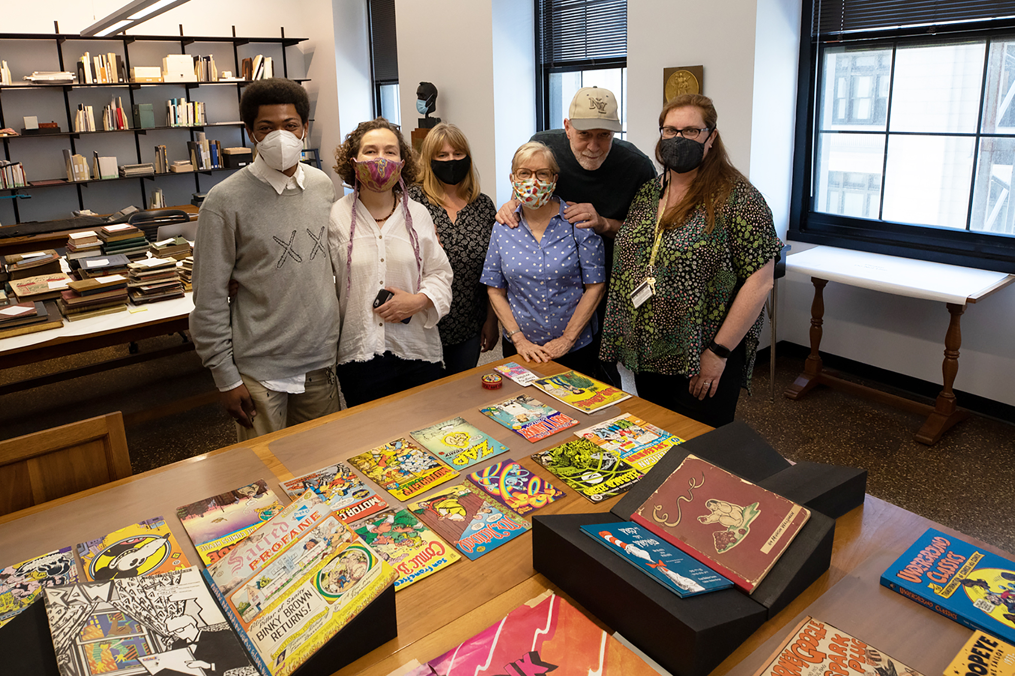 Adler, his wife and library staff pose in front of comix collection