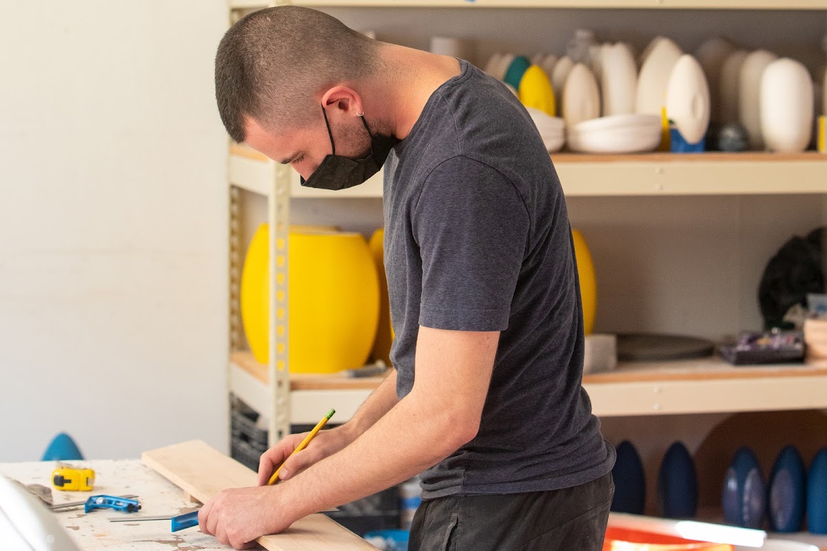 Student measures and cuts wood in a studio while masked