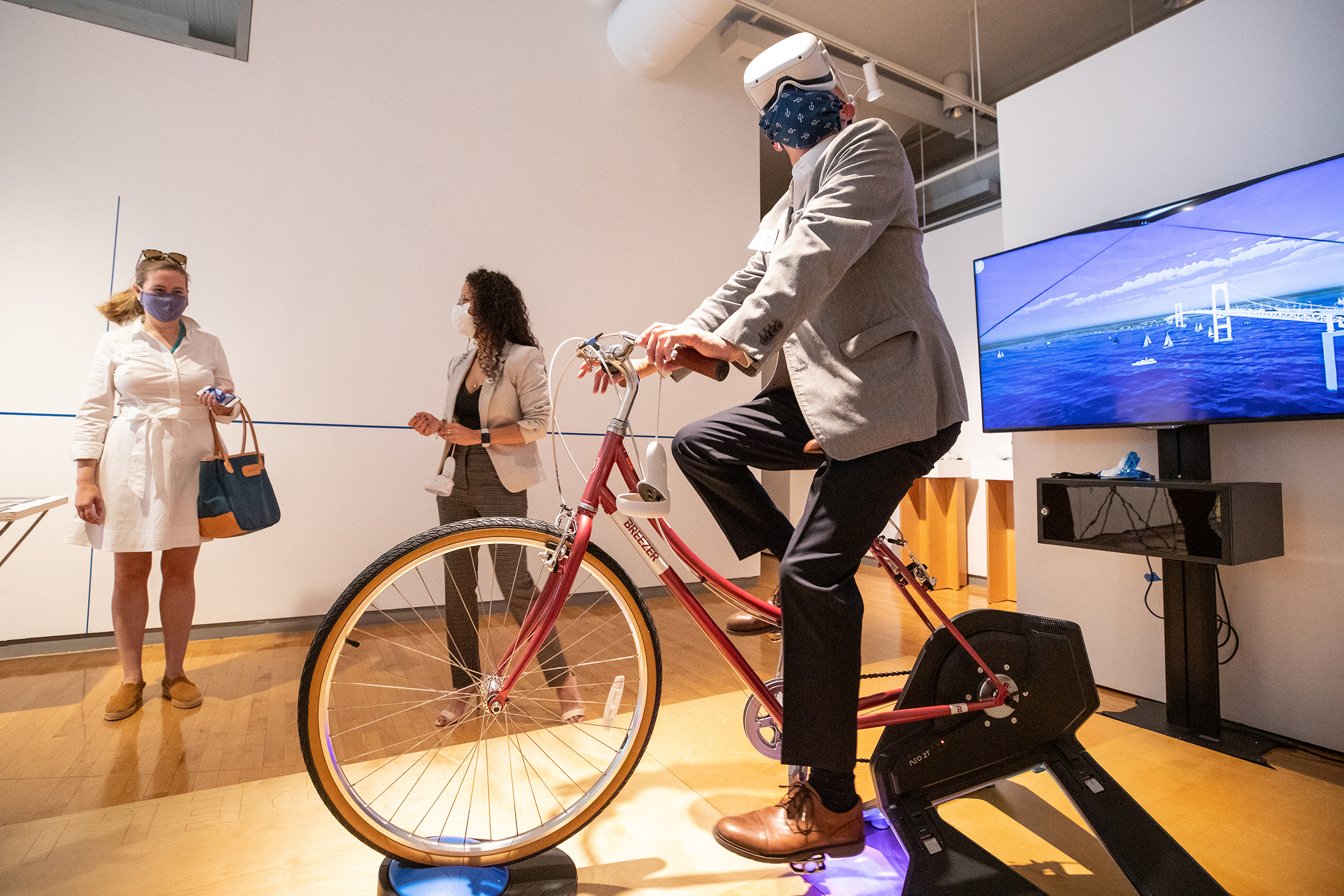 a visitor tries out VR goggles while riding a stationary bicycle