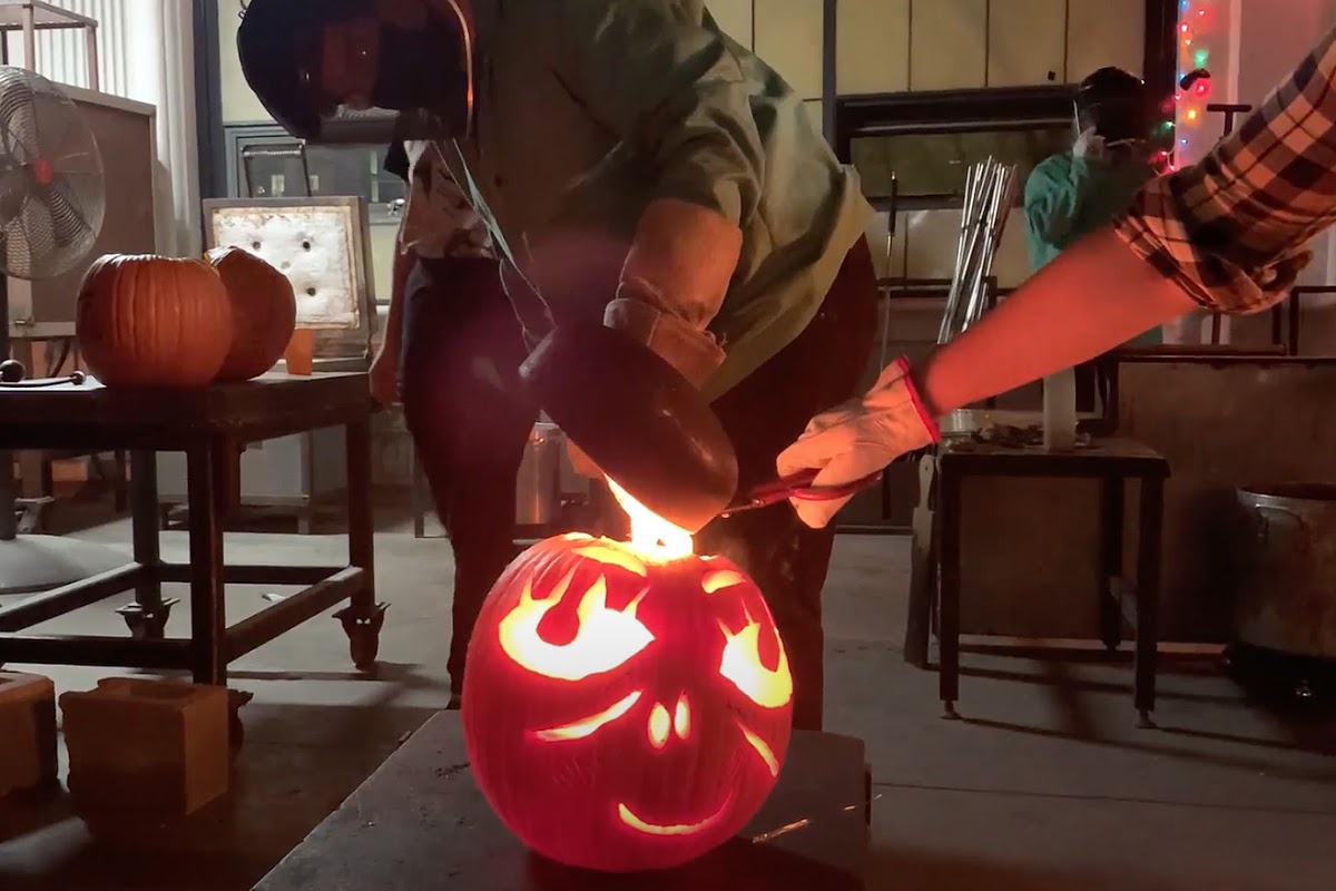 Glass majors poured molten glass into a jack-o-lantern in the hotshop