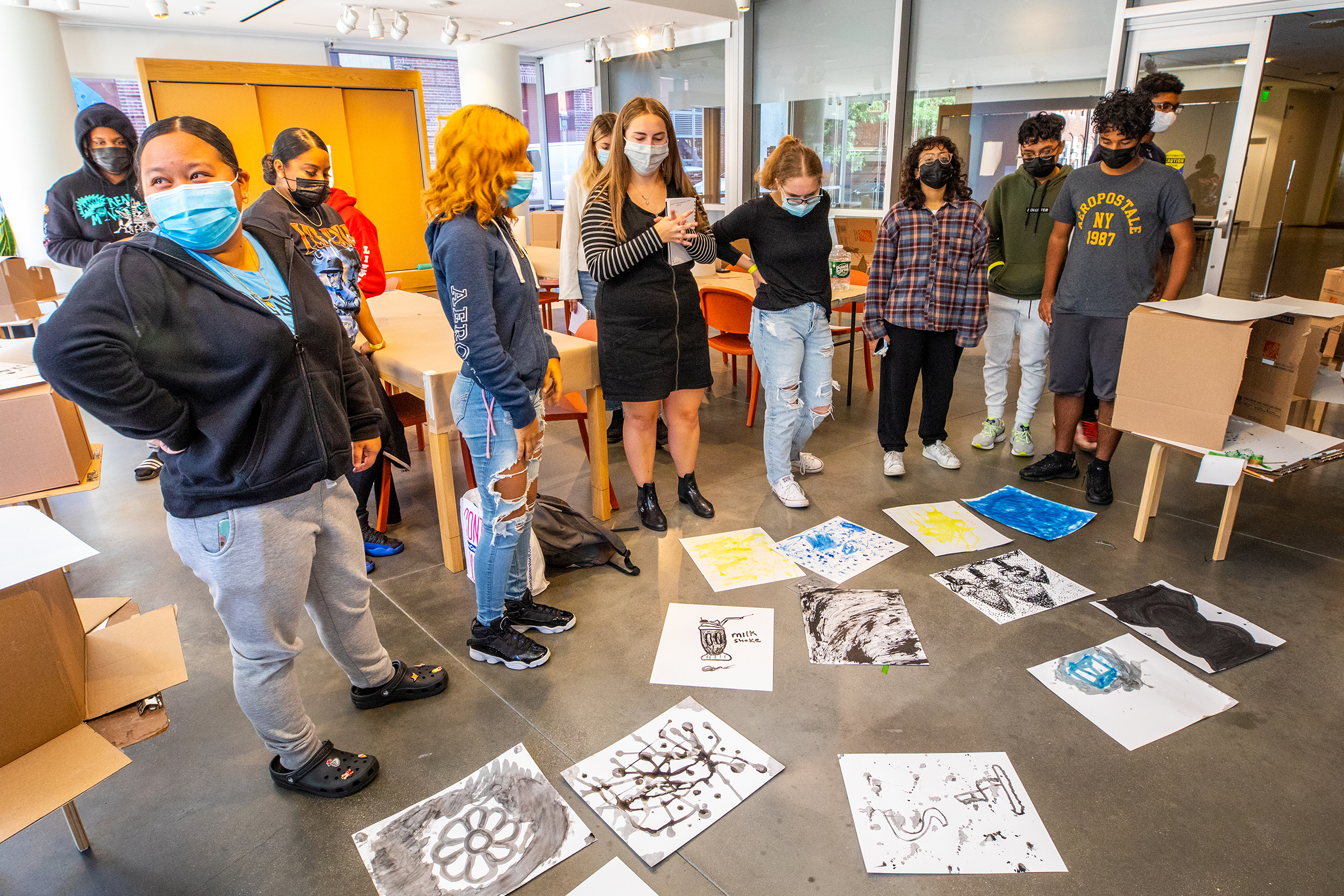 the group examines completed paintings laid out on the floor