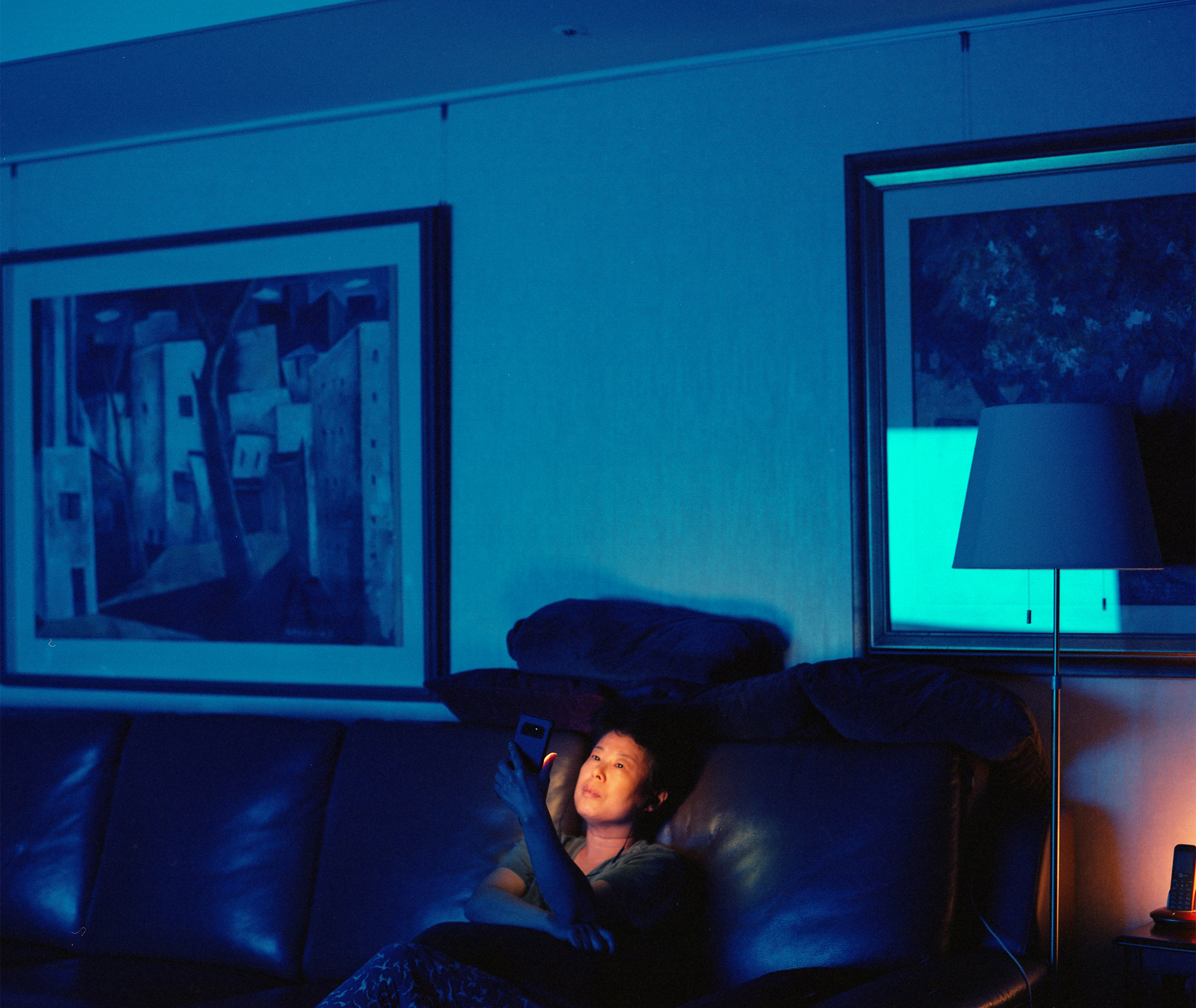 a woman's face is lit by her cell phone in an otherwise darkened room