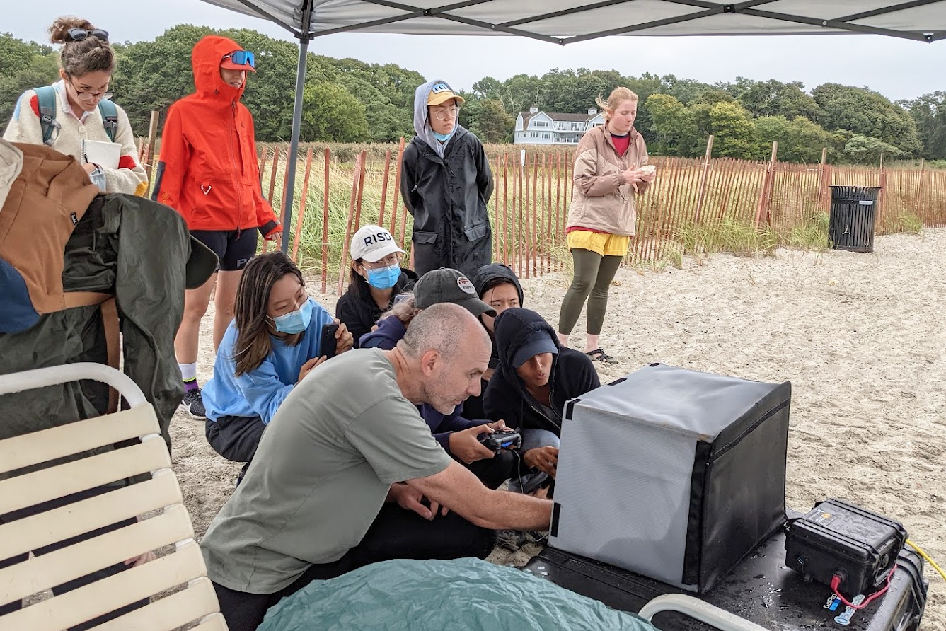 Cooke and students watch the data feed into a laptop on the beach