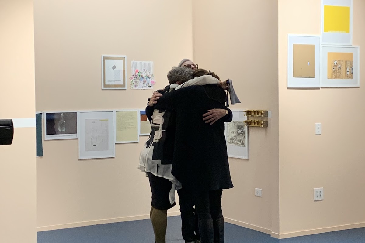 People hugging at cultural center exhibition