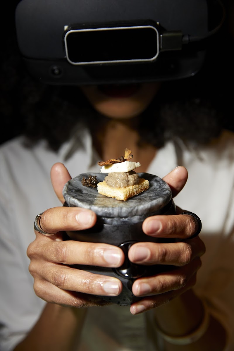 Person wearing VR googles reaching out and holding actual food, RISD faculty member Mattia Casalegno