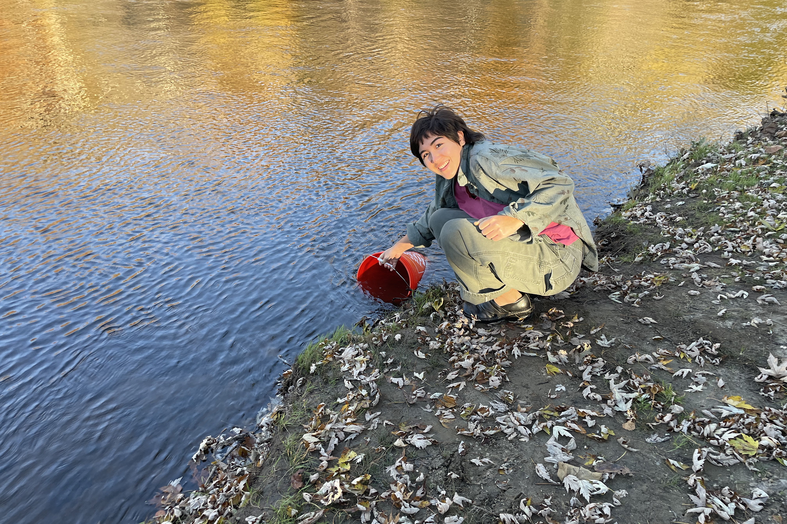 a student collects water samples from the river