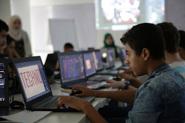 Young Syrian men working on laptops in class