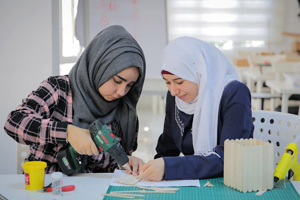 Young Syrian women working on a project with power tools