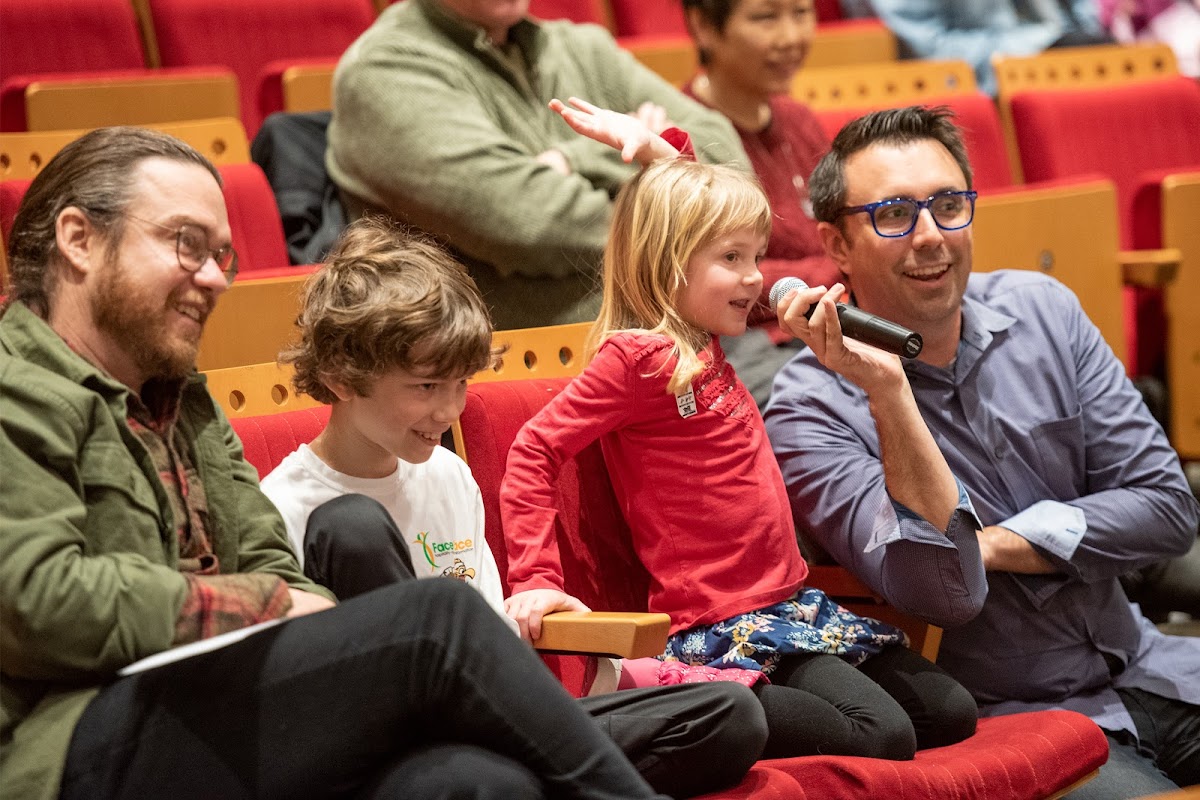 Child in audience speaks into a microphone held up by Jarrett J. Krosoczka 99 IL