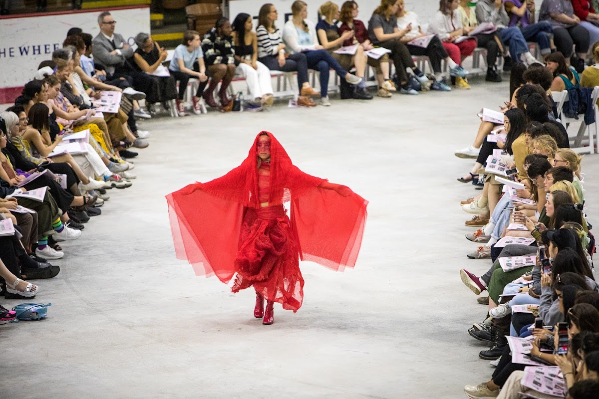 Model on runway wearing a piece in a red chiffon collection by Elizabeth Sheveley 19 AP