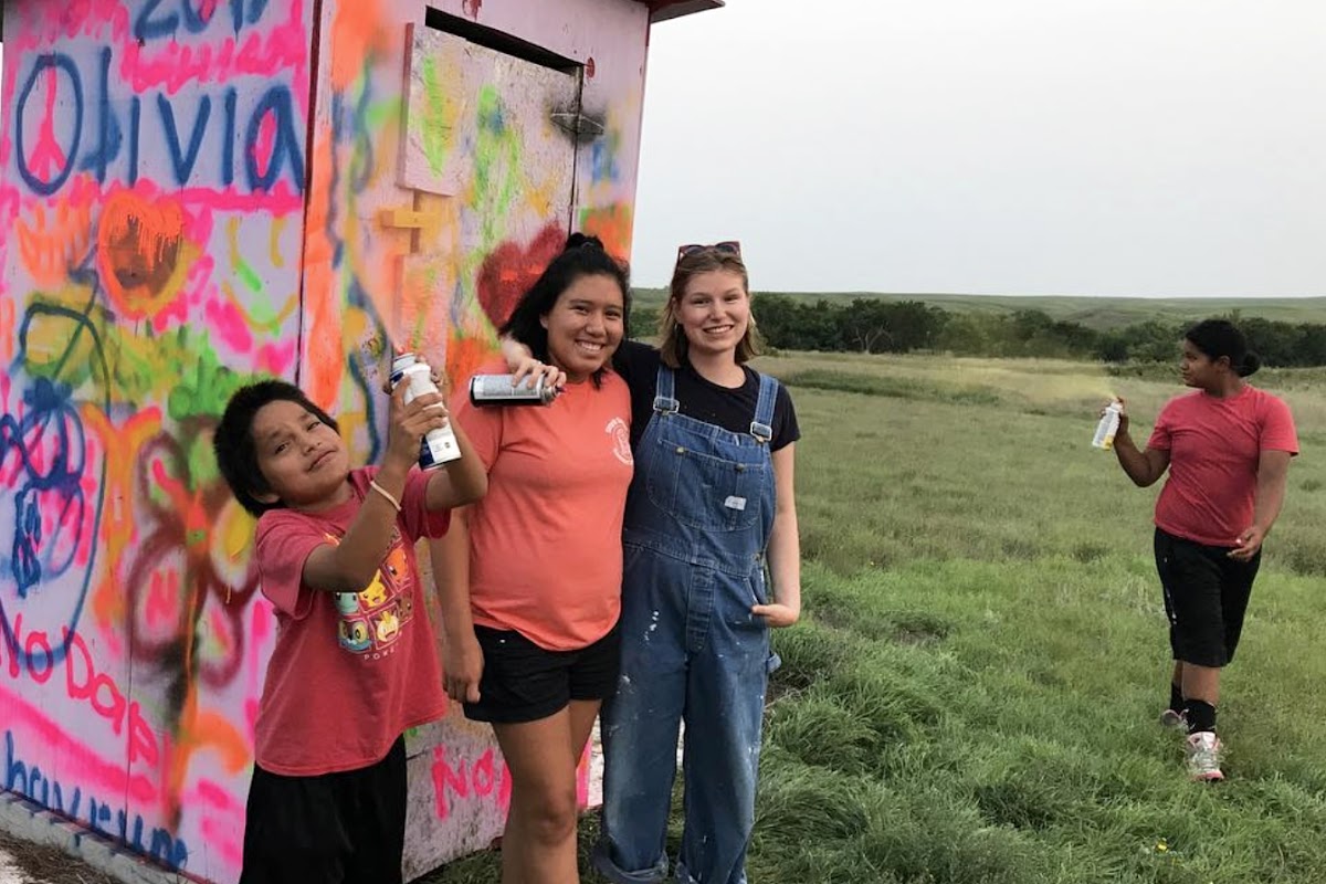 Four people by a graffiti-covered shed on the Cheyenne River Reservation in South Dakota