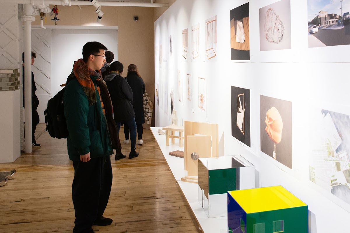 Student looks at a wall of work from one of the Architecture exhibitions