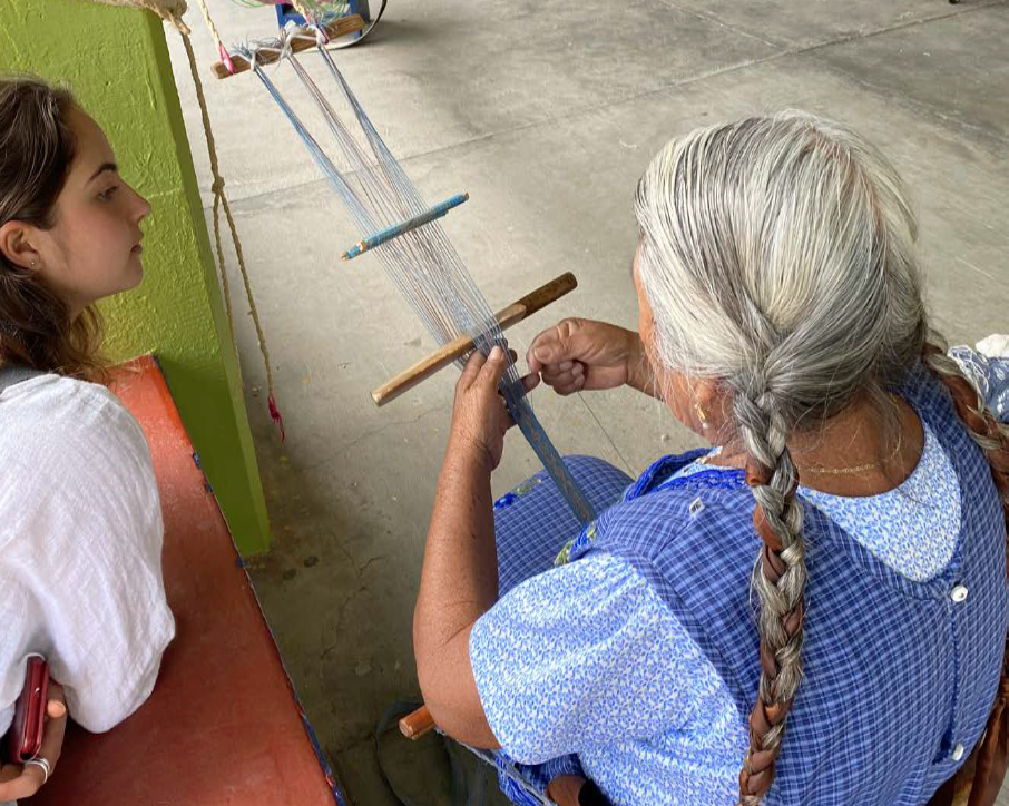 Student watches as woman weaves