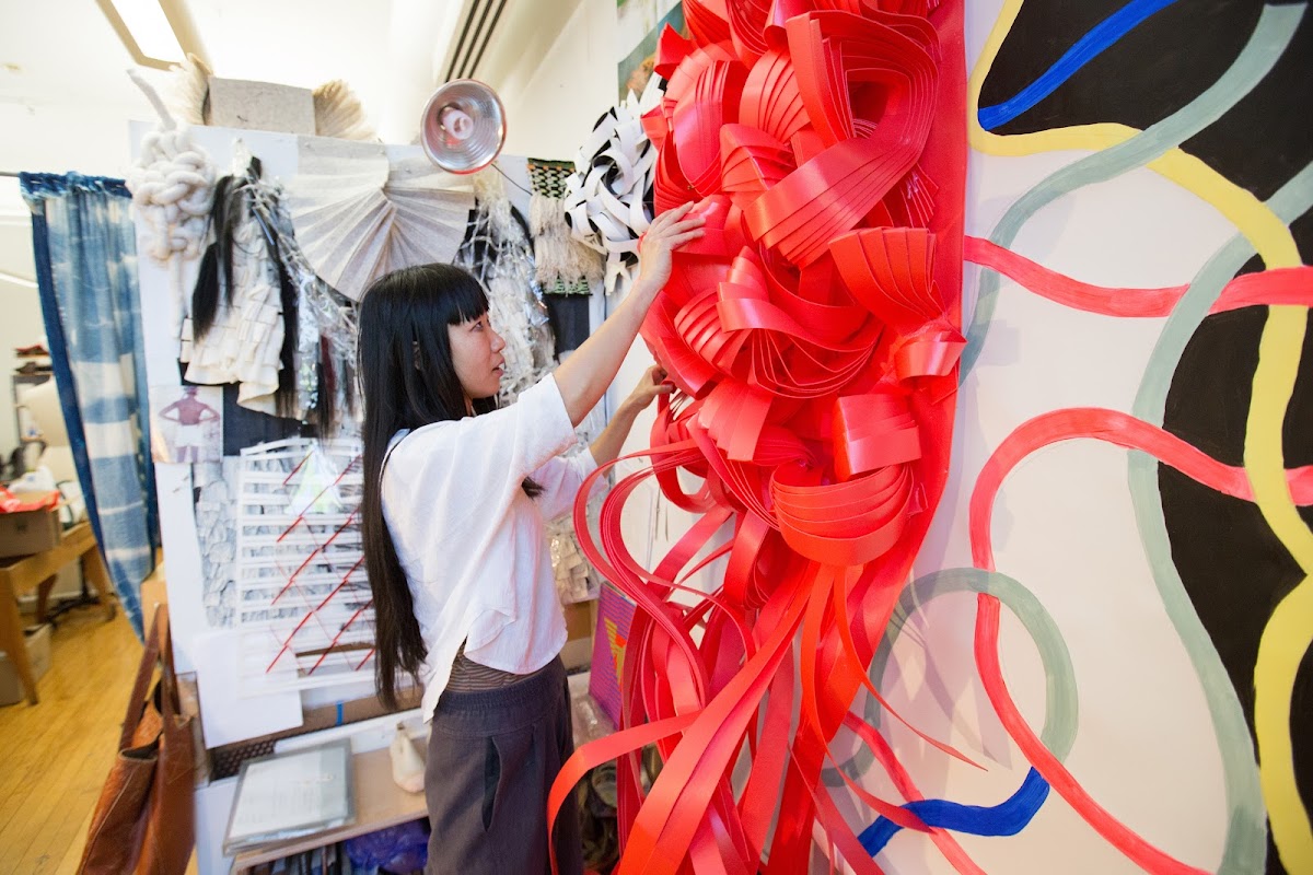 Student working on a red sculpture in a RISD studio