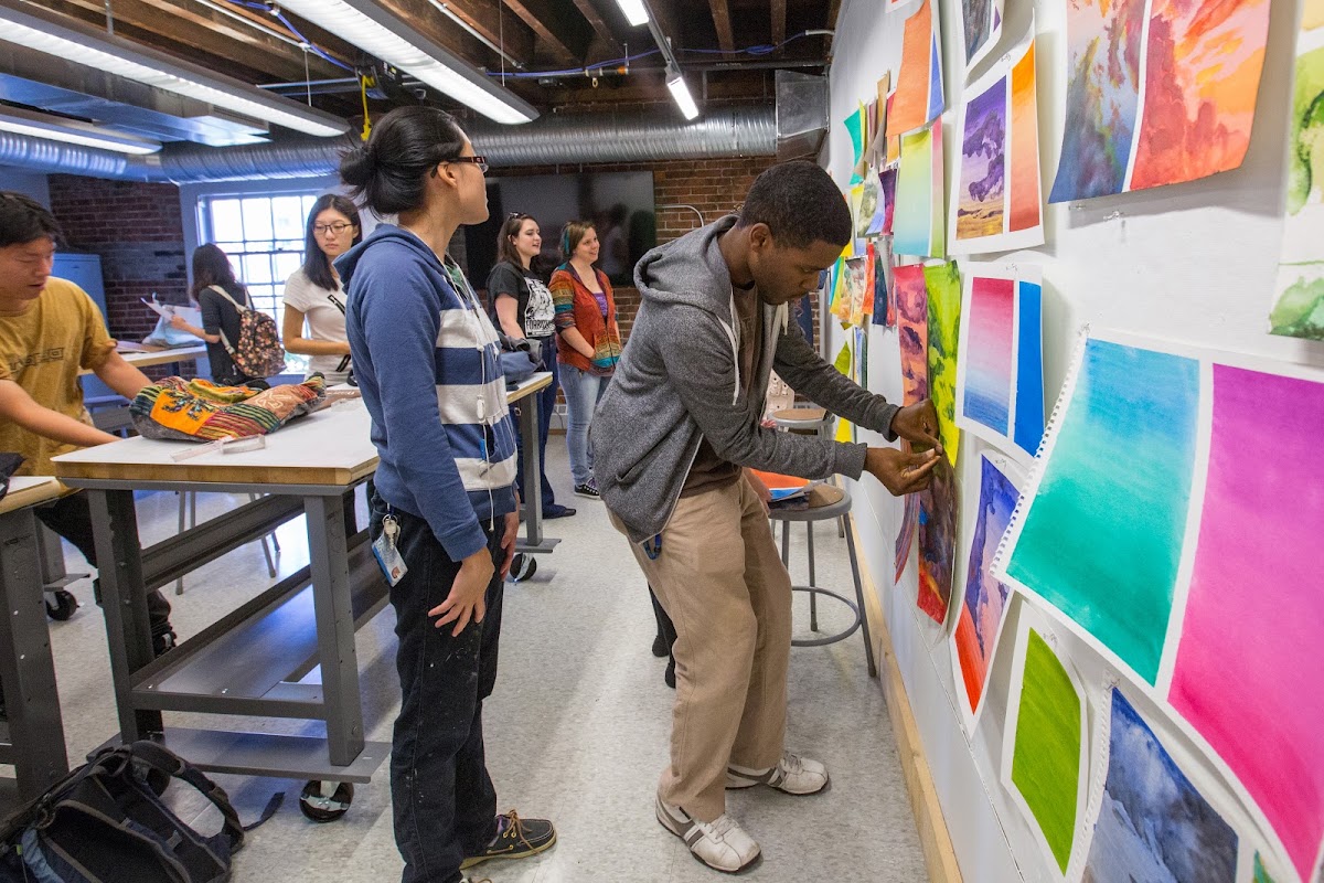 Students tacking up work on the wall of a studio