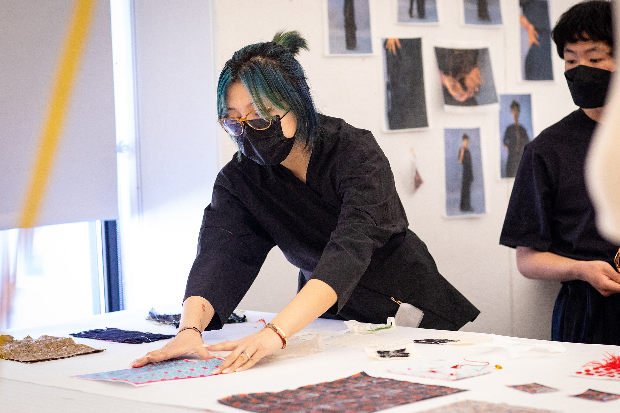 a student arranges work on a table for presentation