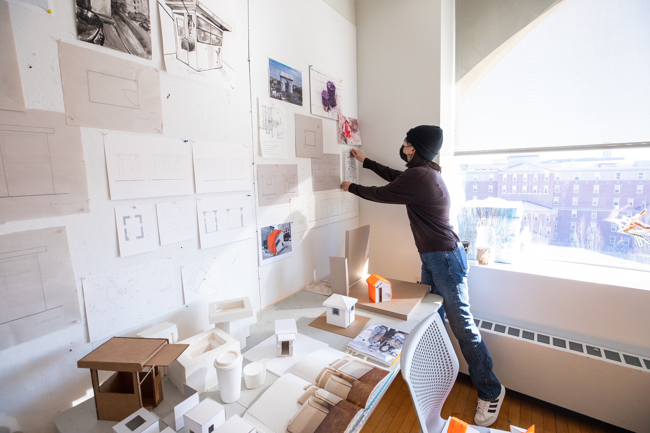 a student pins work to the wall for critique