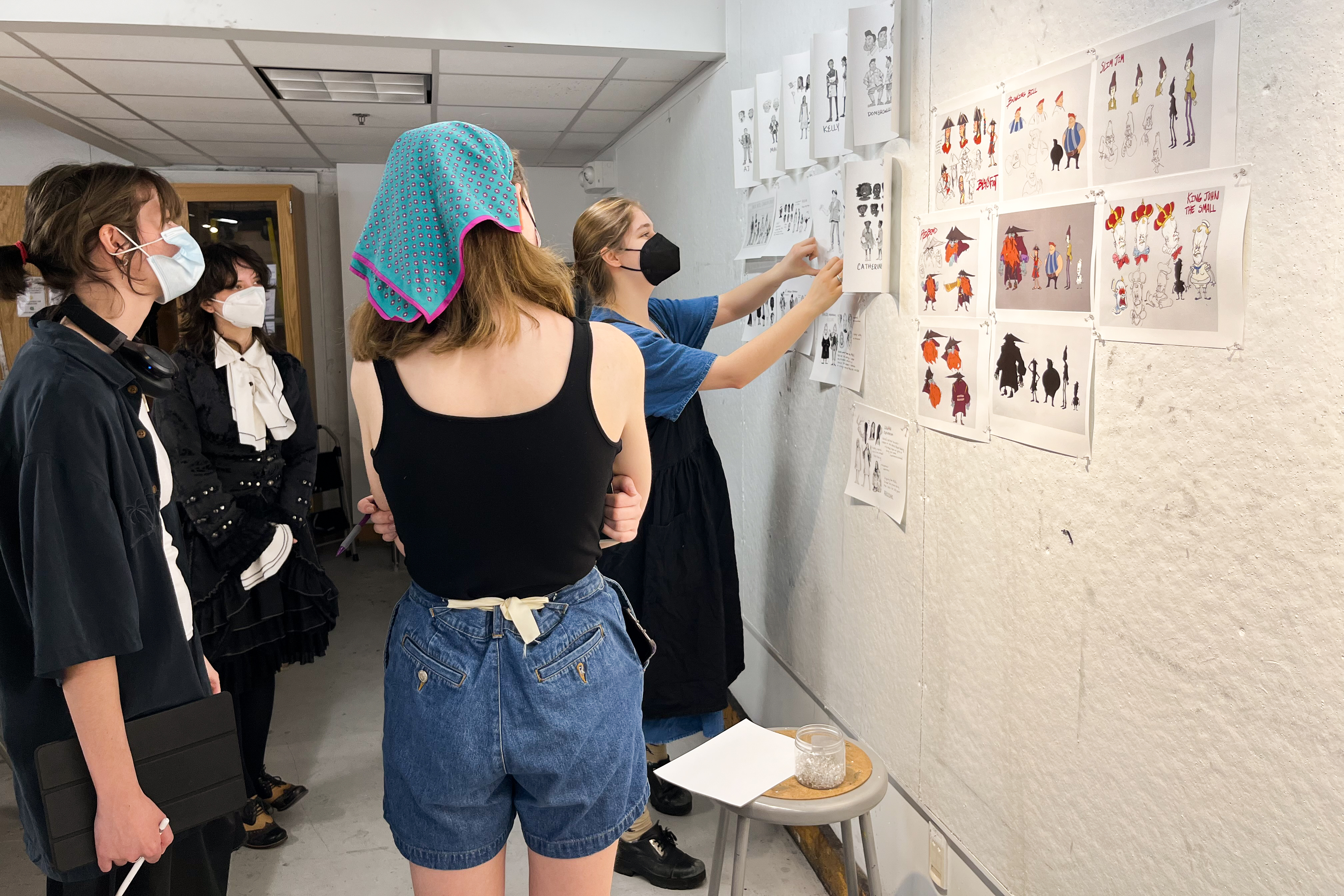 a group of students discuss work pinned on the wall