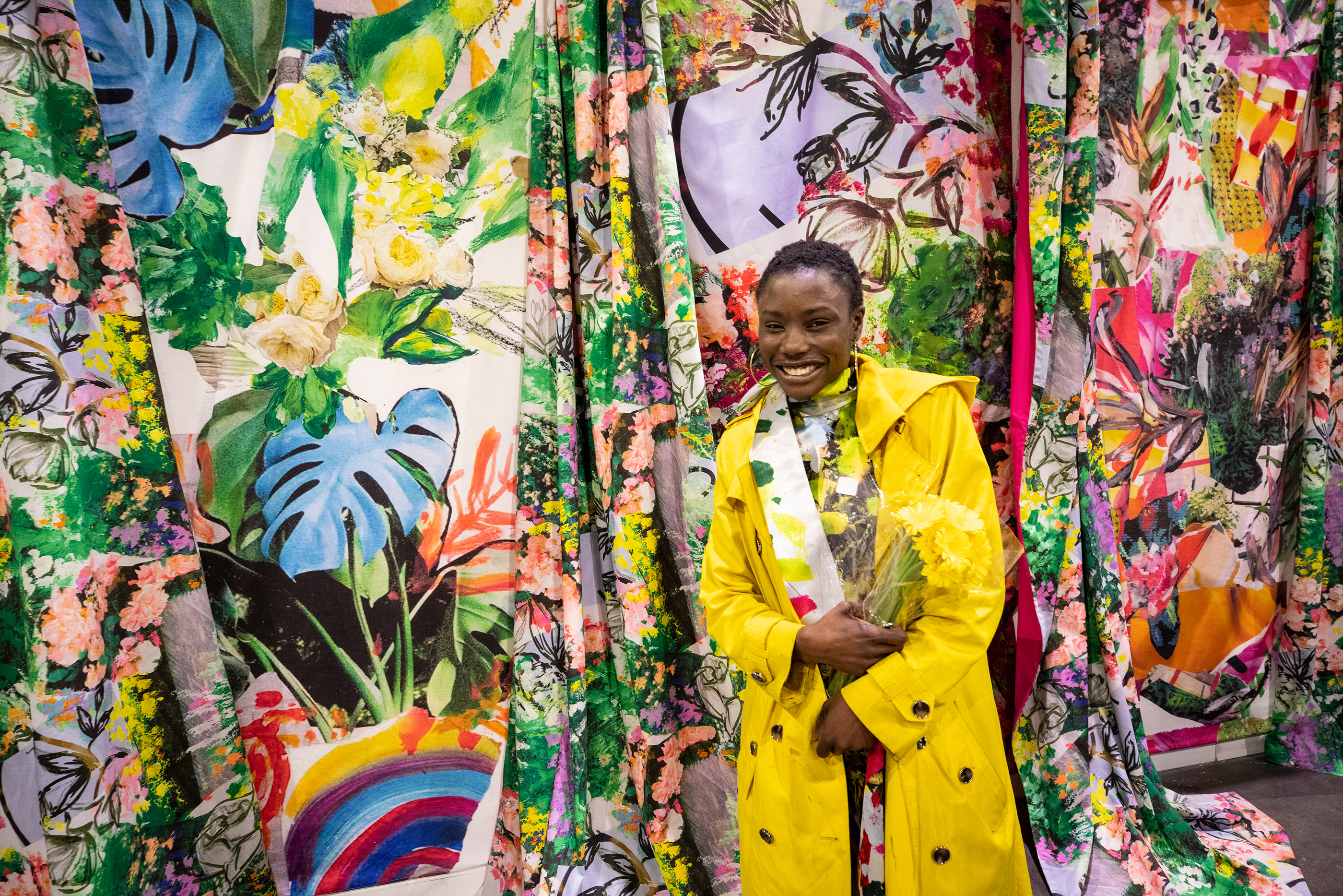 student with flowers poses in front of tropical textile