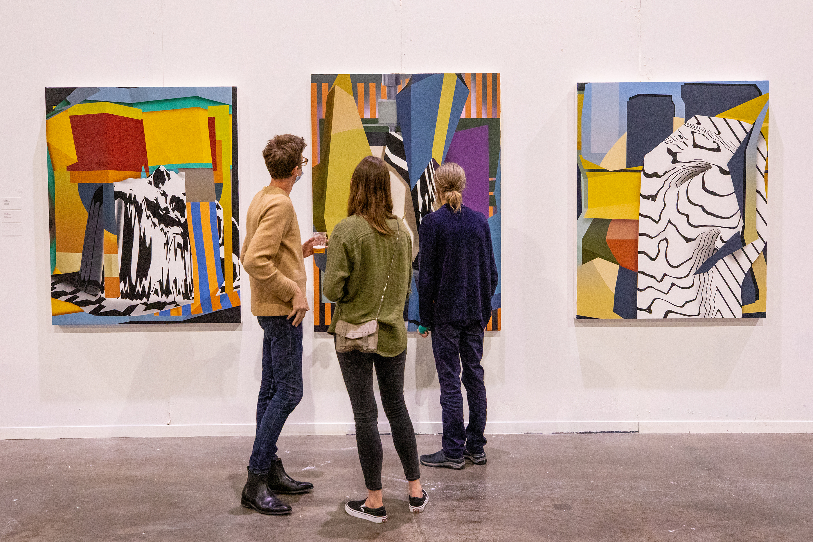 viewers study three abstract paintings