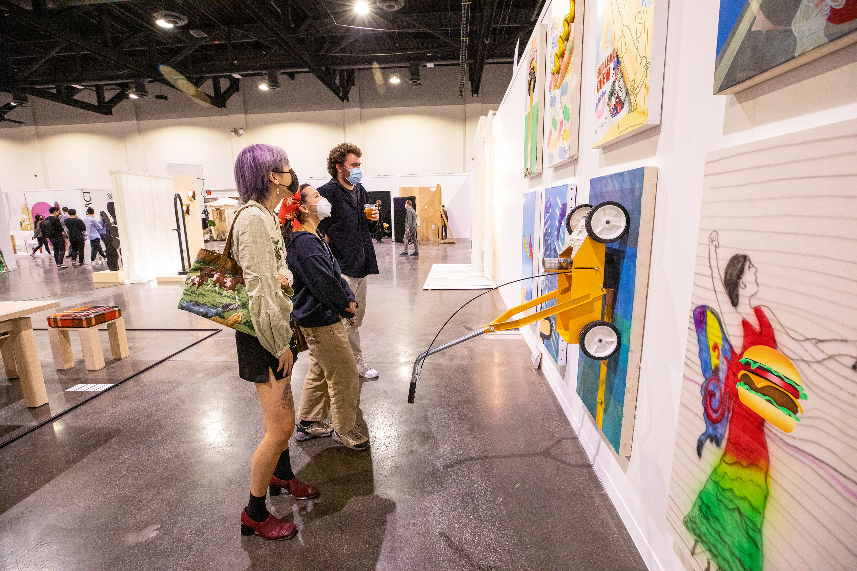 viewers study a wall of paintings