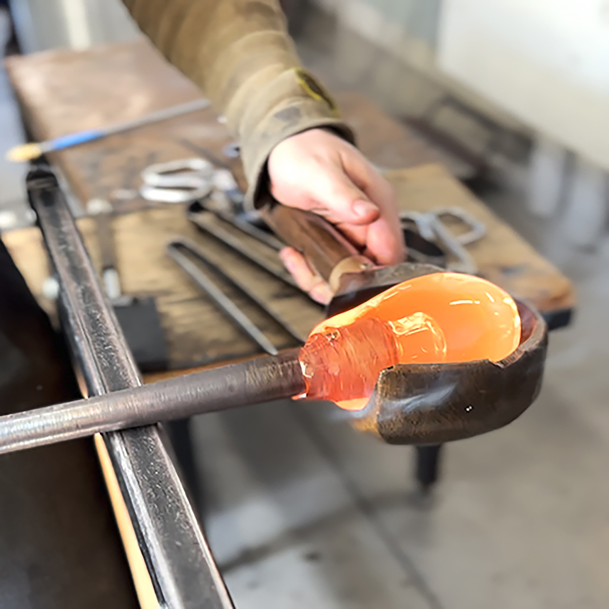 hands working with molten glass in the hot shop