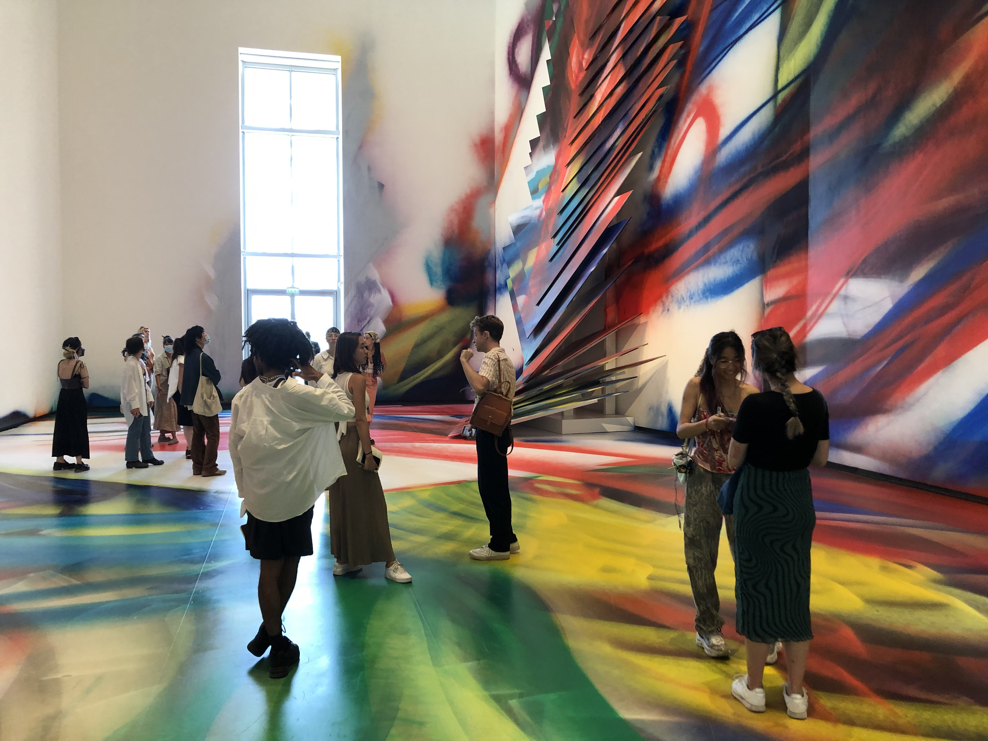 students gather inside an extremely colorful gallery space