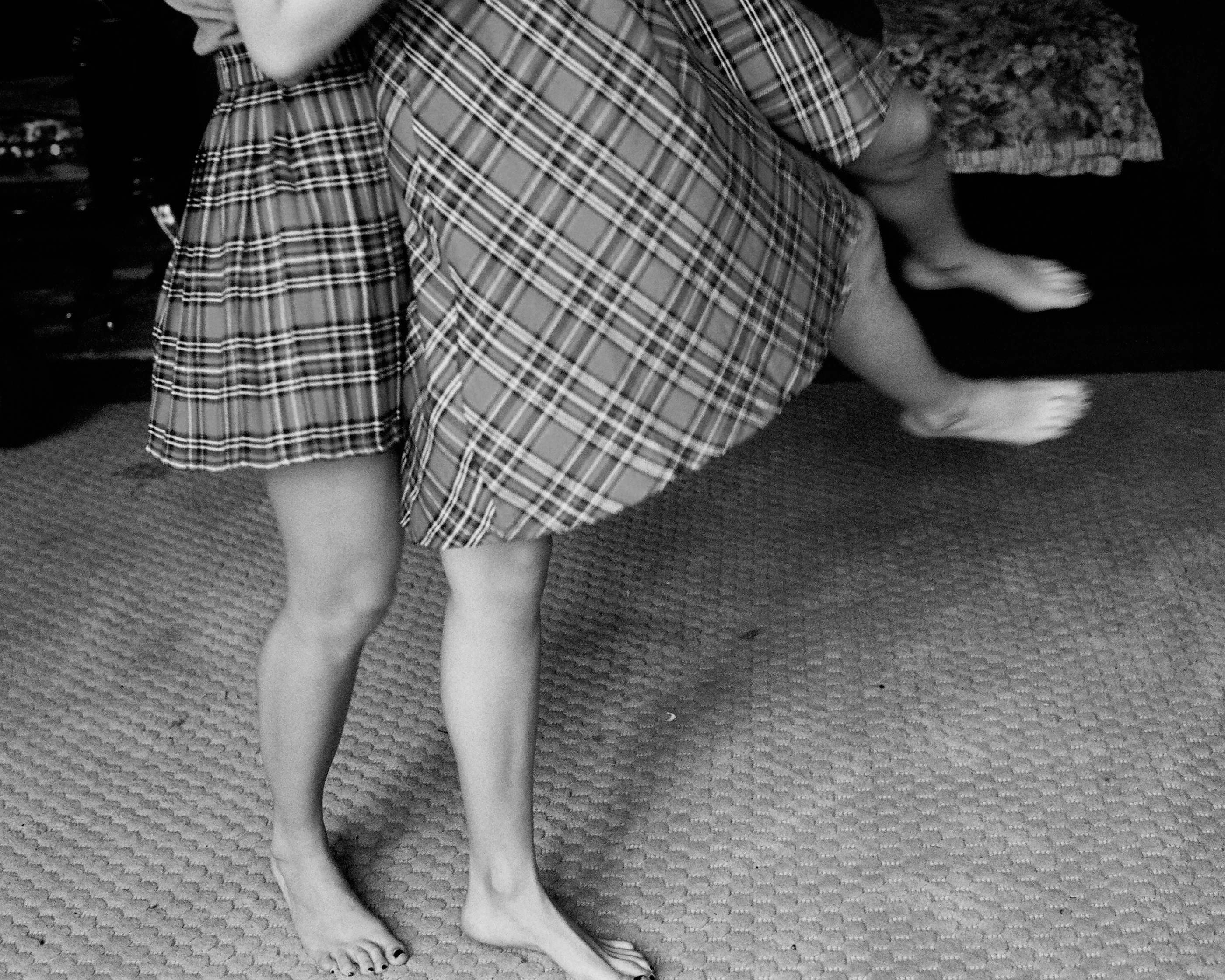 black-and-white image of girls in plaid skirts dancing