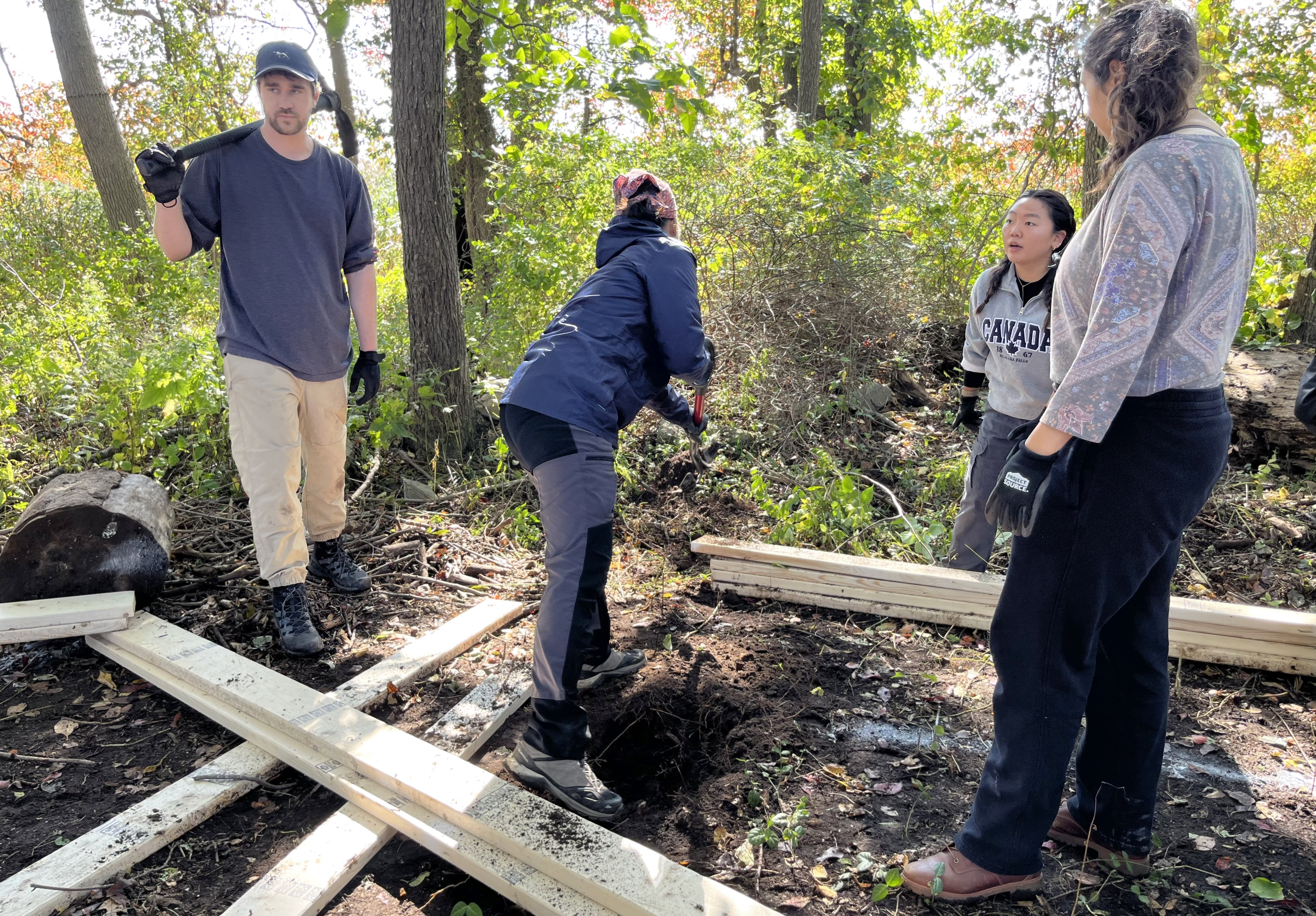 students in the woods digging footings for installation