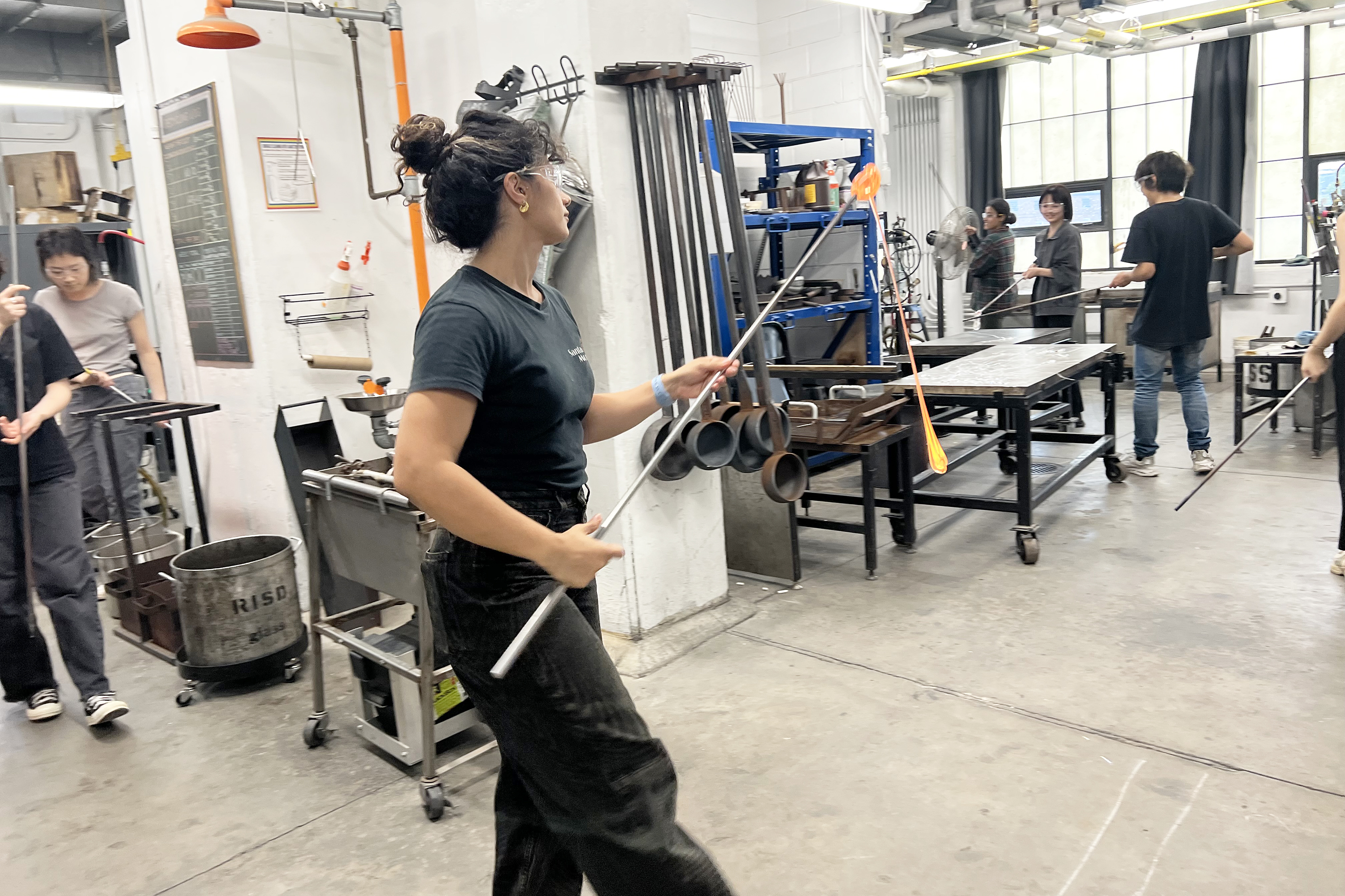 a student with a long metal rod dipped in molten glass