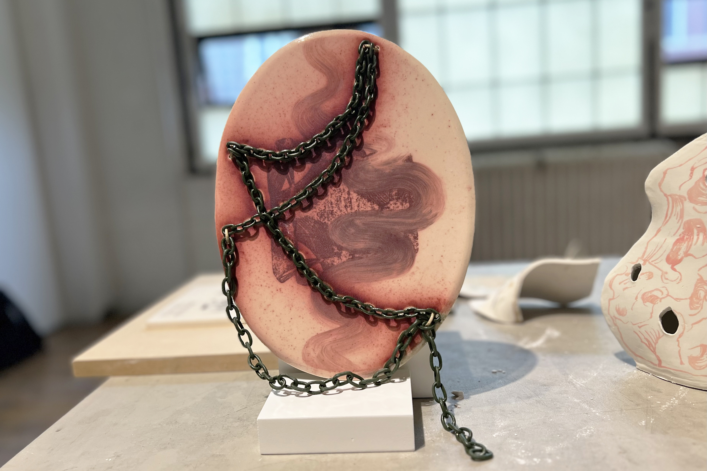 flat, oval piece with chain by Dora Chen