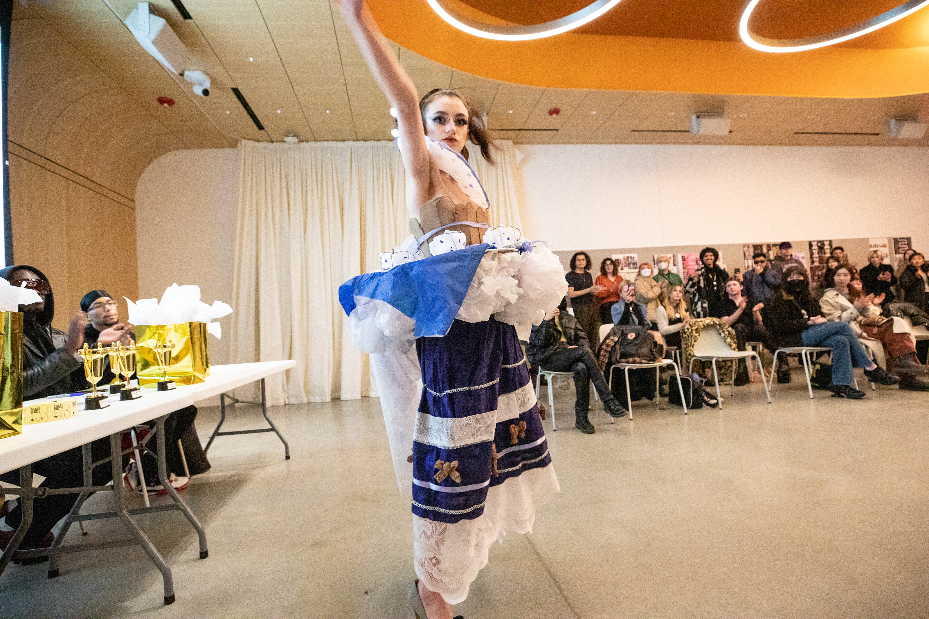 A model poses in Maya Muravlev's blue and white garment, which features paper and wire tea cups around the model's waist and neck