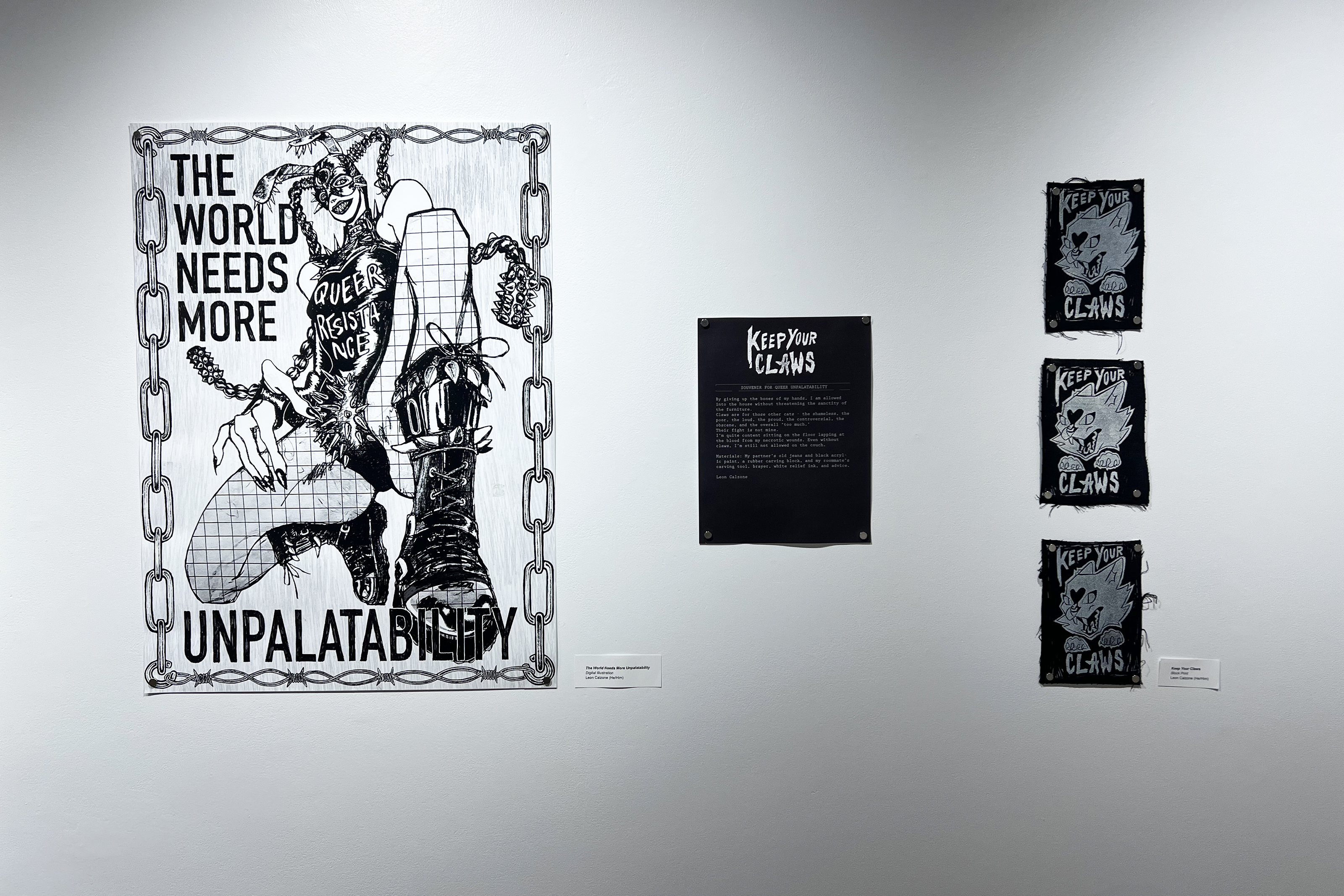 A Black and white print that says "the world needs more unpalatability" by Leon Calzone hangs in the isb gallery