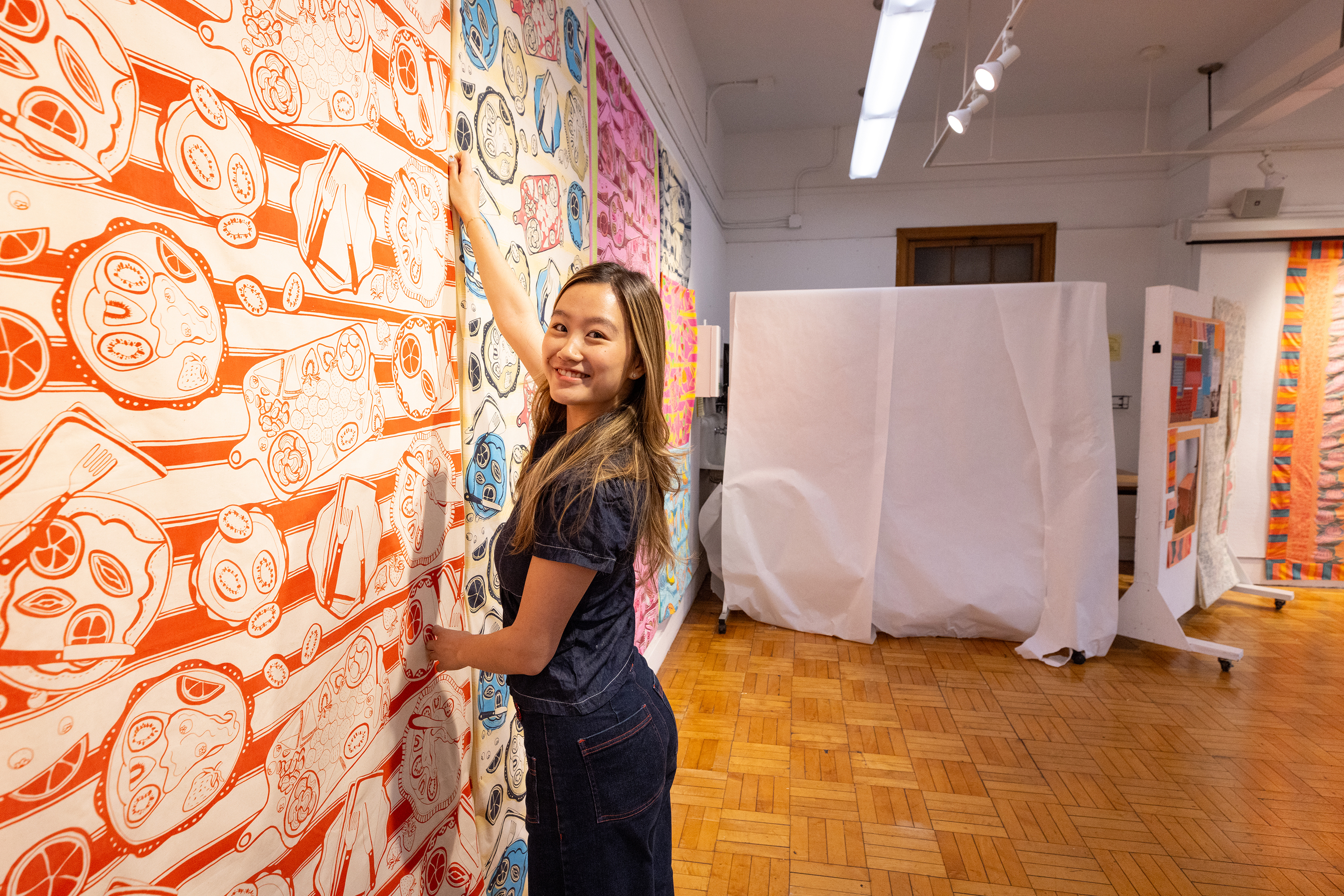 Textiles student pinning up colorful work for crits