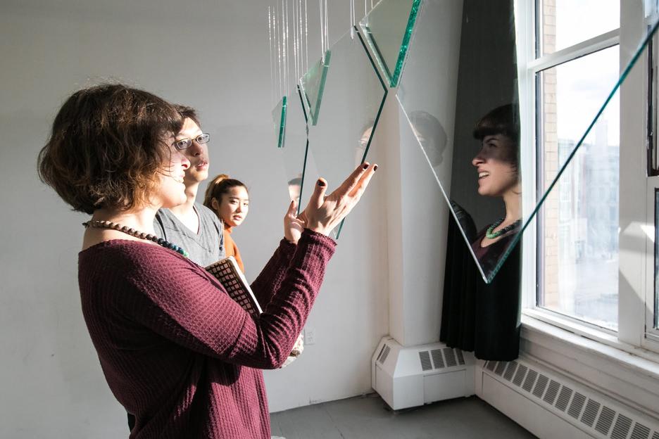 Instructor explaining a hanging glass sculpture to students