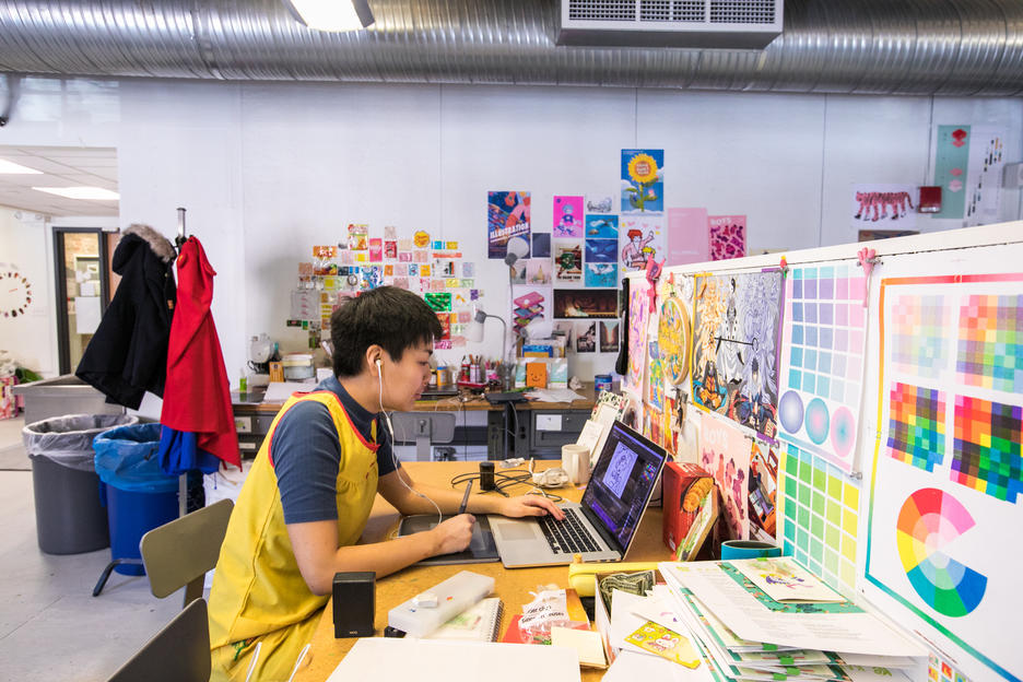 a RISD student works at a desk with a dividing wall covered with color samples