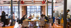 RISD students sitting at a long conference table or at workstations inside the Co-Works Research Lab