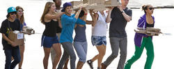 a group of RISD Pre-College students walking outdoors, with several carrying a large architectural model