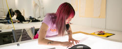Apparel student with pink hair measures pattern.