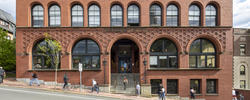 students walking on the sidewalk in front of the red brick Waterman Building on RISD’s campus