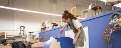 furniture design student paints a blue object in the upholstery studio