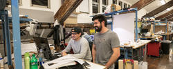 Two arch students laughing in studio in front of computer.