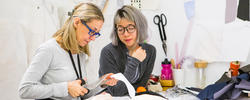 a Rhode Island School of Design Apparel Design faculty member cuts fabric as a student looks on