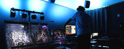 student working on a synthesizer in a darkened sound studio