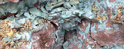 A rock formation of mostly gray, red and white clay