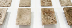a three row, four column grid of rectangular, off-white clay pieces elevated on a white surface