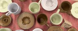 green brown and off-white mugs on a red and white tablecloth